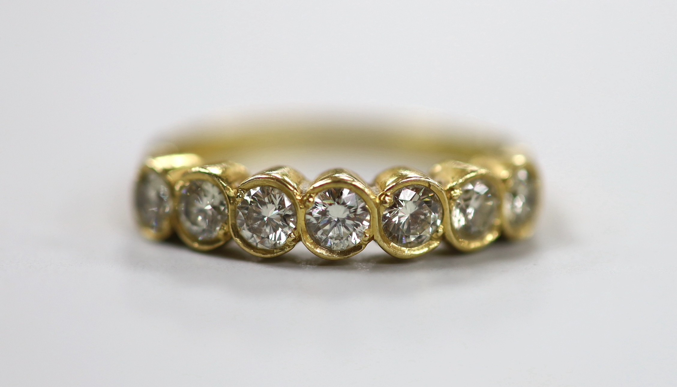 A modern 750 yellow metal and seven stone diamond set half hoop ring, size O, gross weight 3.2 grams.